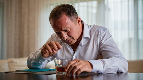 Мужчина с алкогольной зависимостью пьет виски